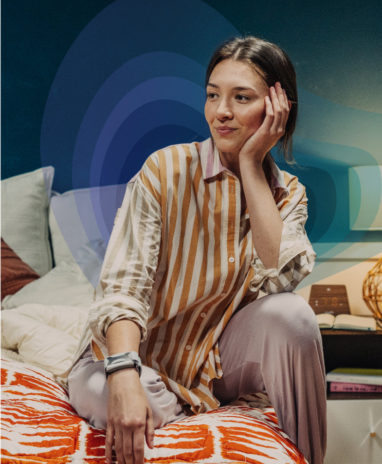 Woman sitting on bed wearing apollo wearable
