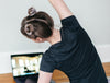 A woman watching a yoga video and following along