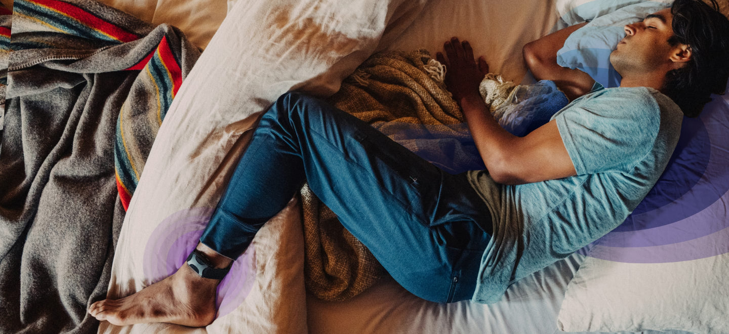 Man asleep in bed wearing Apollo on his ankle