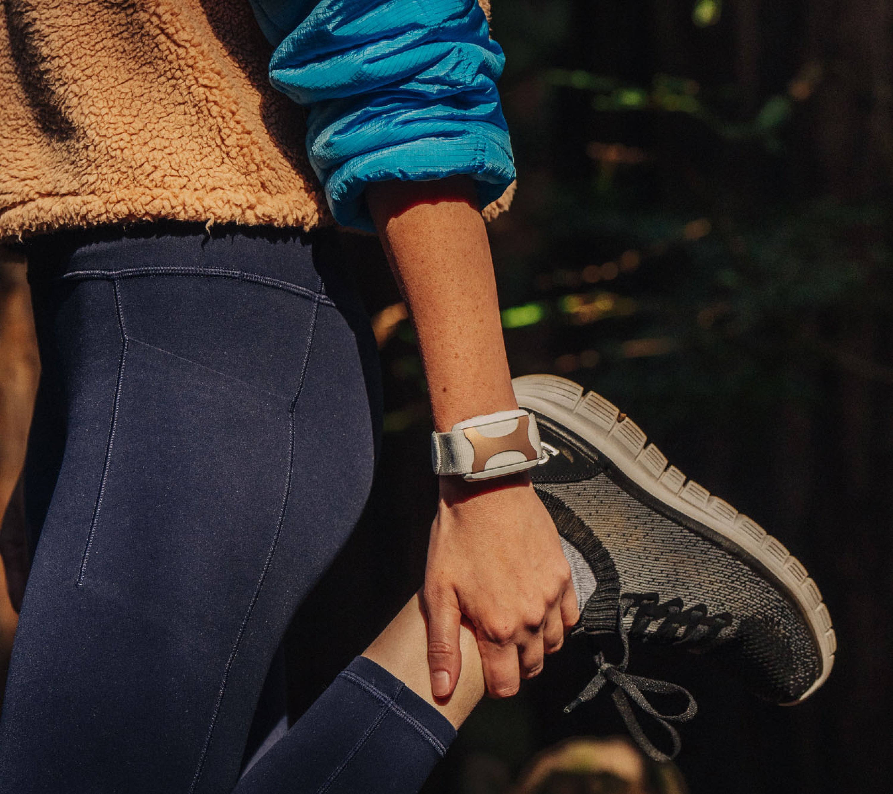 Women doing a quad stretch holding her foot with a Rose Apollo wearable