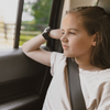 Young girl looking out window in back seat of car with seat belt on and an Apollo wearable on her right wrist