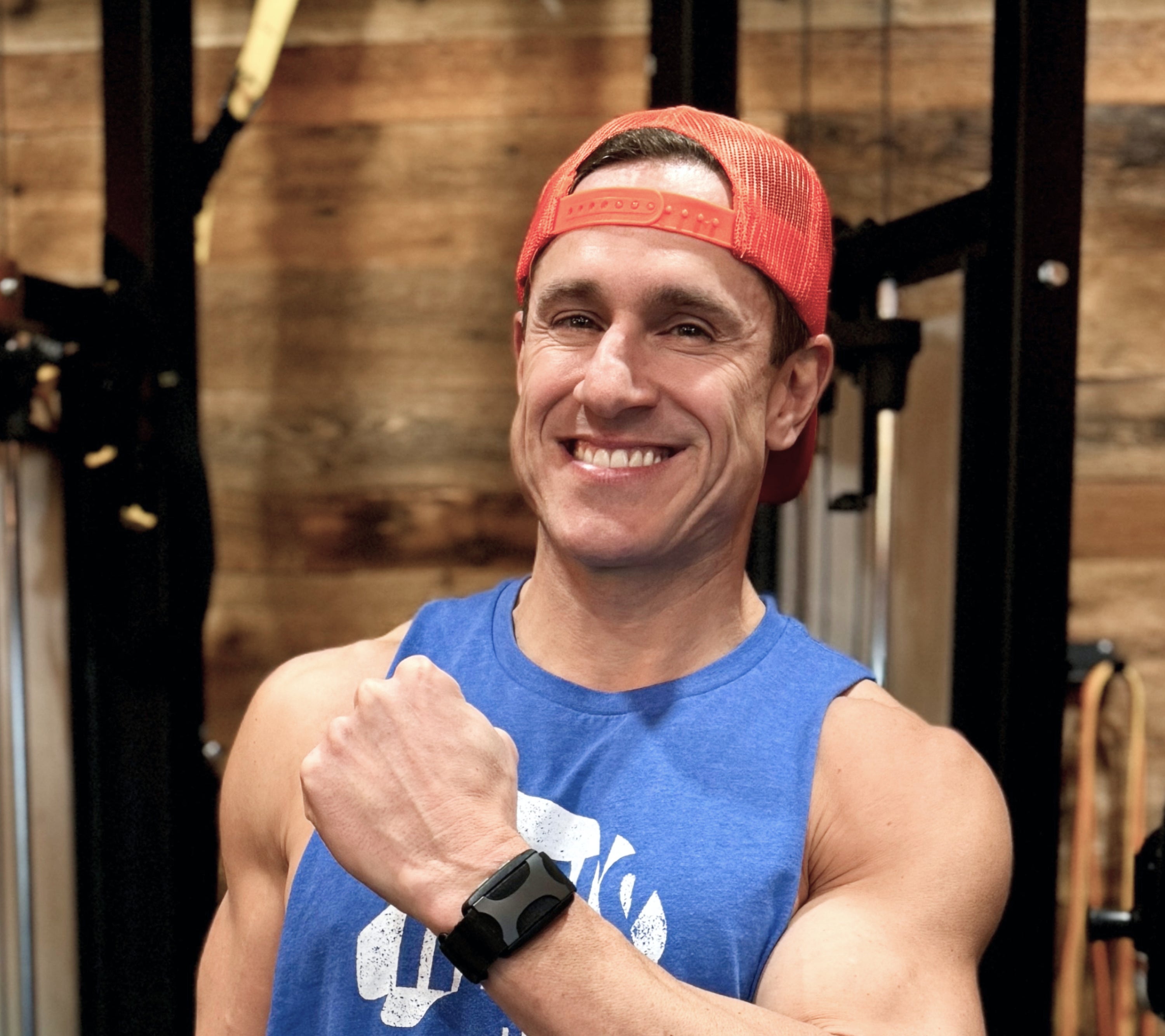 Don Saladino in a blue tank top with a red backwards trucker hat. he has an apollo wearable in black on his left wrist.
