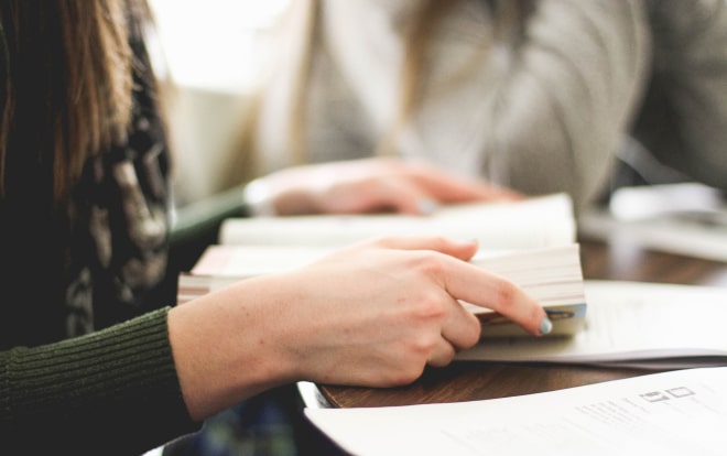 Women with dark brown long hair and white skin holding open a novel
