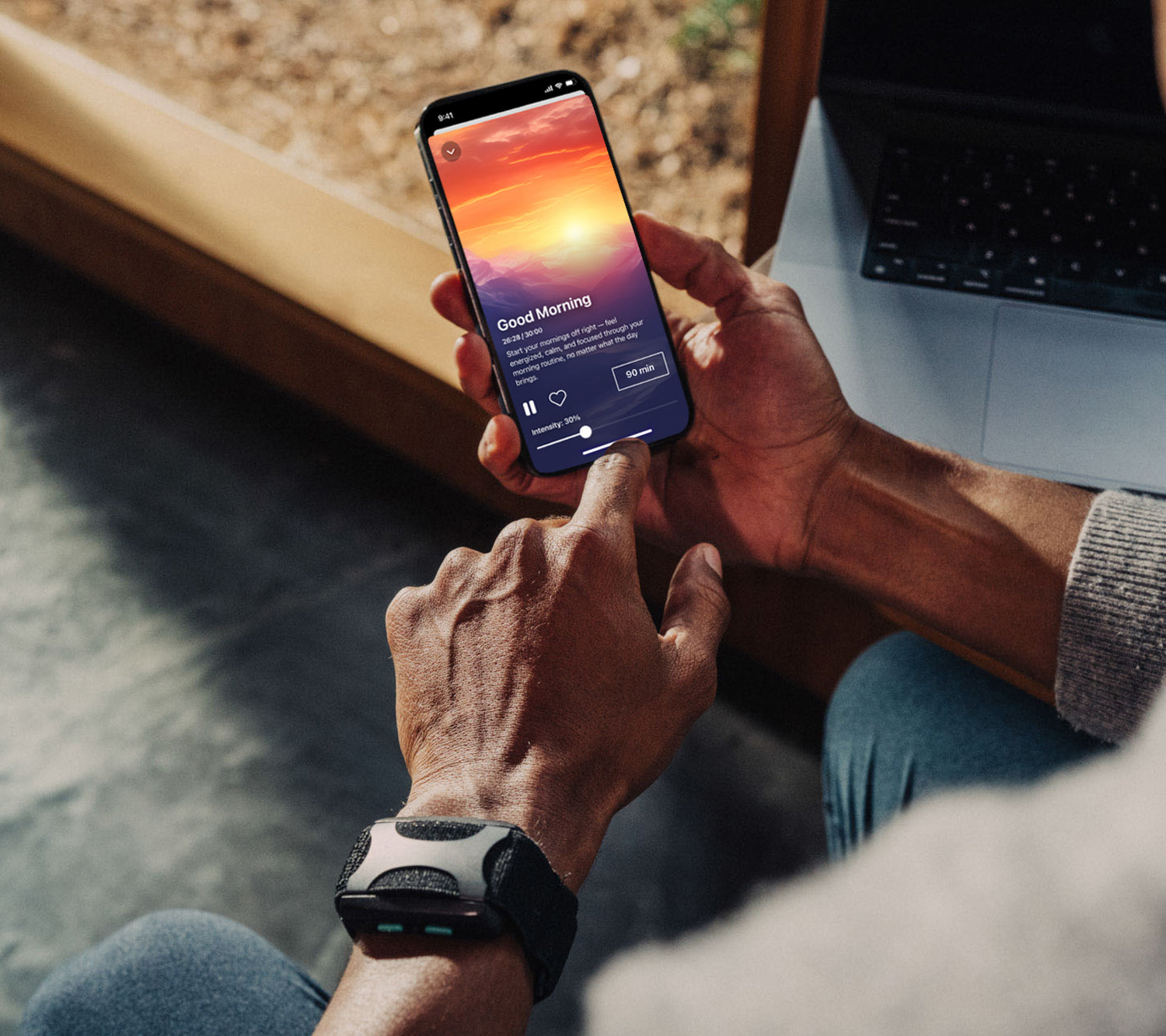 man holding an iphone with apollo neuro app up on the screen playing Good morning Vibe. he is wearing an Apollo wearable in Stealth on his left wrist.