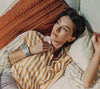 Women in striped shirt laying in bed with an Apollo wearable on her right wrist
