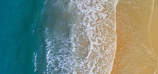 Aerial view of a wave crashing on the beach.
