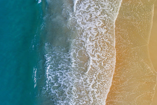 Aerial view of a wave crashing on the beach.
