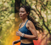 Women jogging in the forest wearing a blue tank top with Apollo wearable on left wrist.