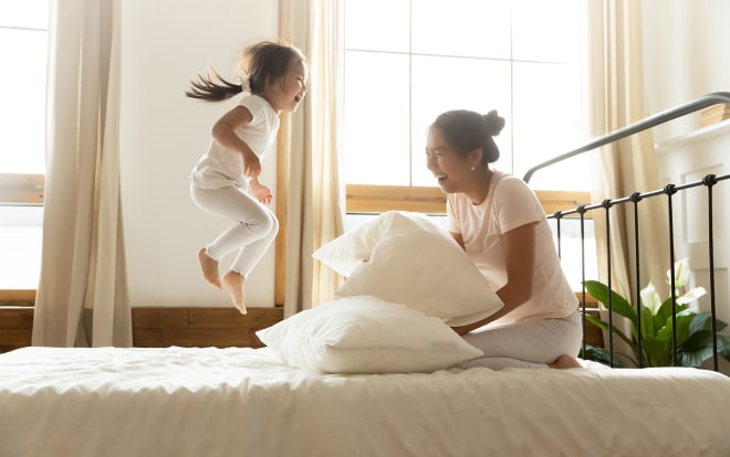 Woman and her daughter laughing in bed