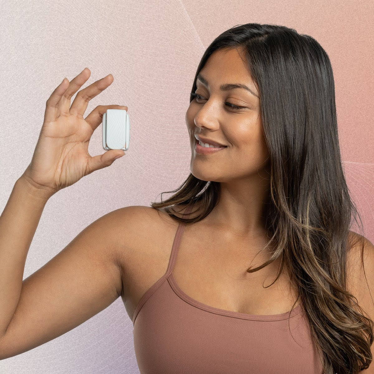 Female holding Apollo Neuro device on a clip in her hand