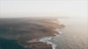 video cover image of a ocean waves hitting coastline from high up view