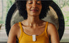 Woman meditating while wearing Apollo with a Clip with gong behind her